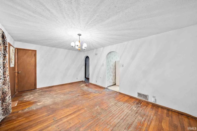 spare room with wood-type flooring, a textured ceiling, and a chandelier