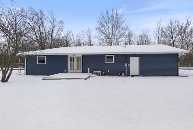 snow covered back of property with central air condition unit and french doors