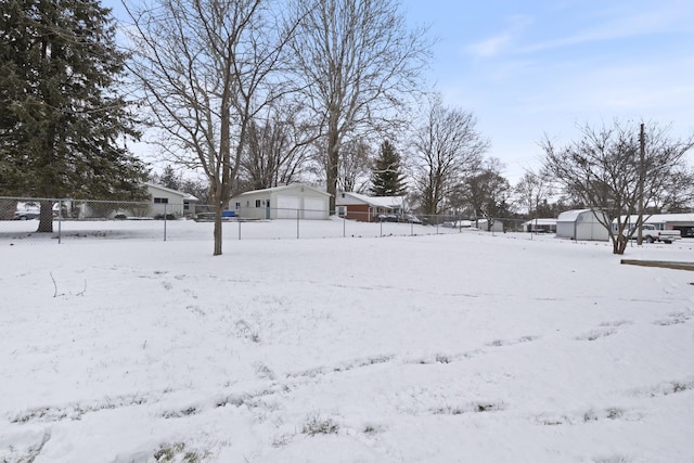 yard layered in snow featuring an outbuilding and a garage