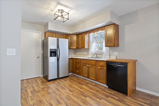 kitchen with sink, stainless steel fridge with ice dispenser, black dishwasher, and light hardwood / wood-style flooring