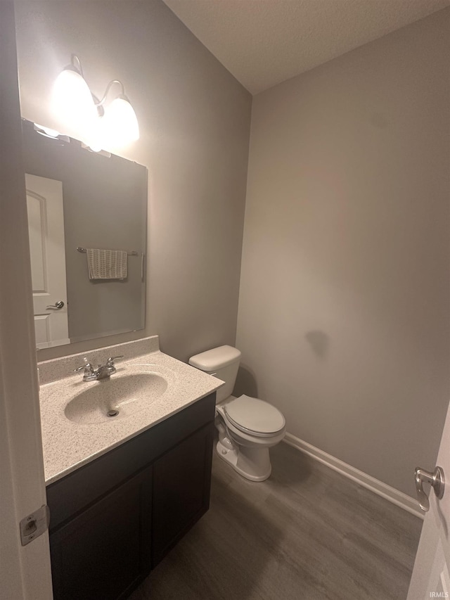 bathroom with hardwood / wood-style floors, vanity, and toilet