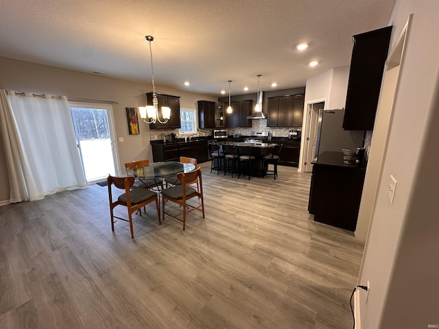 dining room with light hardwood / wood-style floors, a textured ceiling, and an inviting chandelier