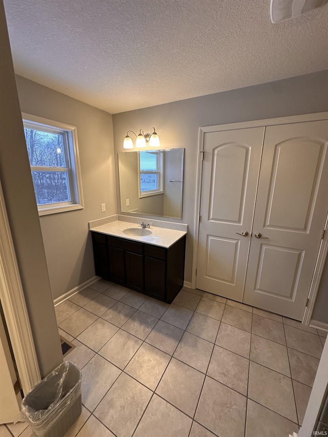 bathroom with tile patterned flooring, vanity, and a textured ceiling