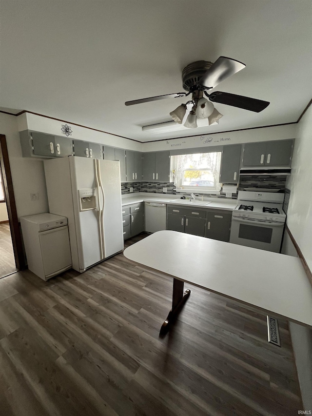 kitchen featuring gray cabinetry, sink, tasteful backsplash, dark hardwood / wood-style flooring, and white appliances