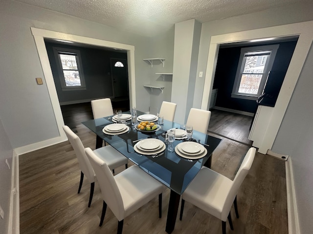 dining space featuring dark wood-type flooring and a textured ceiling