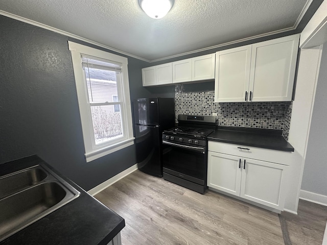 kitchen with stainless steel gas range oven, black fridge, light hardwood / wood-style flooring, and white cabinets