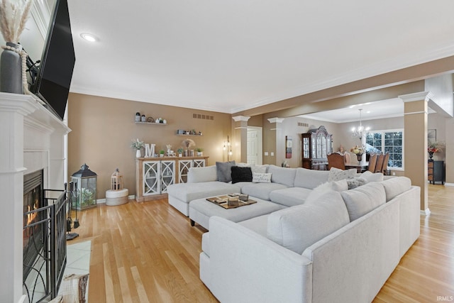 living room with a chandelier, light hardwood / wood-style floors, and ornamental molding