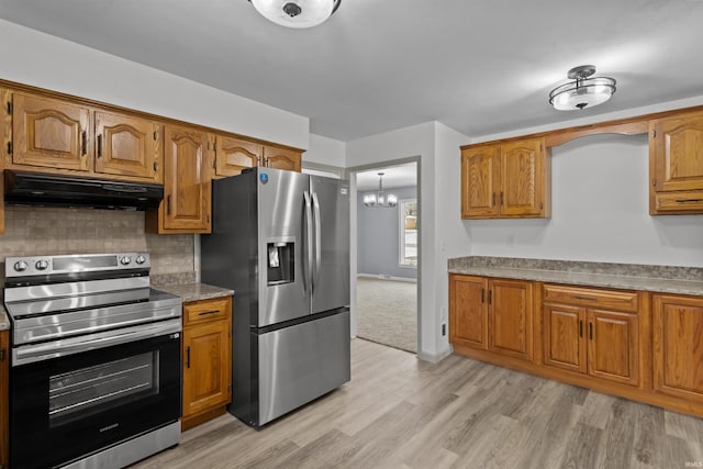 kitchen with a notable chandelier, light hardwood / wood-style floors, backsplash, and appliances with stainless steel finishes