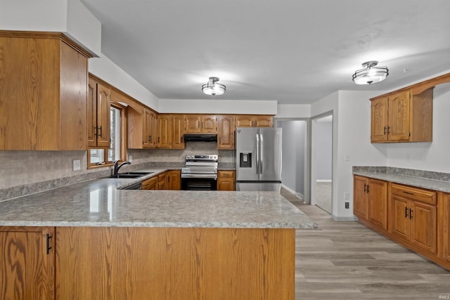 kitchen featuring kitchen peninsula, appliances with stainless steel finishes, light hardwood / wood-style flooring, and sink