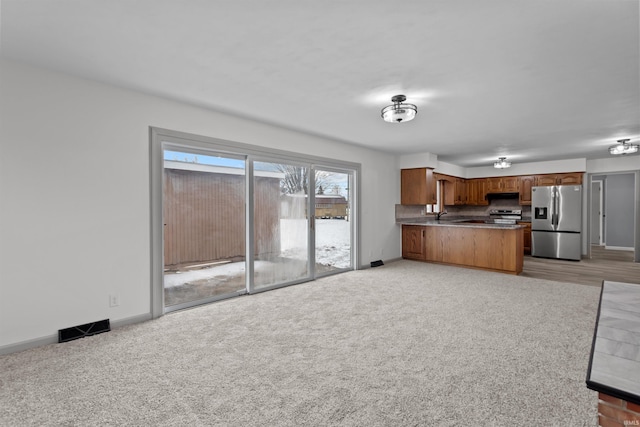 kitchen with sink, stainless steel appliances, backsplash, kitchen peninsula, and light carpet