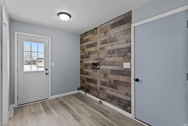 entryway featuring light wood-type flooring and wooden walls