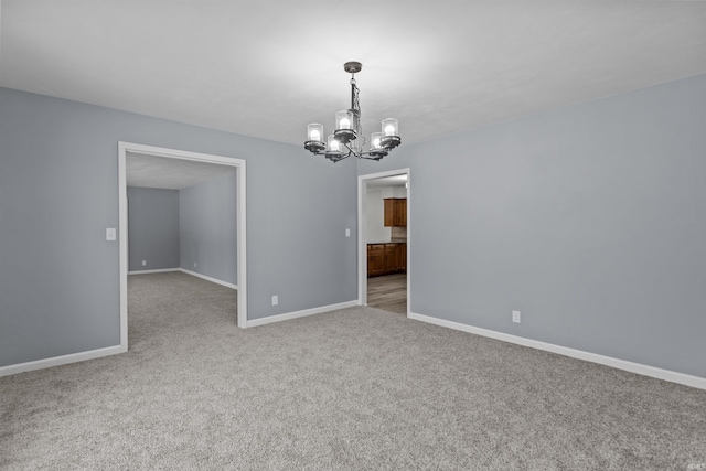 carpeted spare room with a notable chandelier