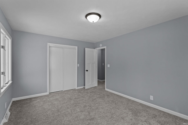 unfurnished bedroom with light carpet and a closet