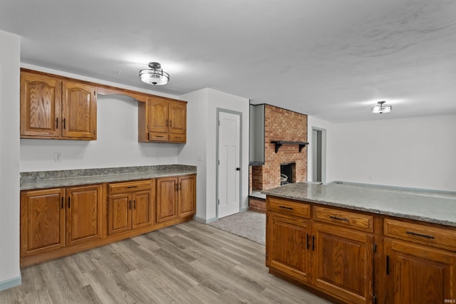 kitchen with a fireplace and light hardwood / wood-style floors