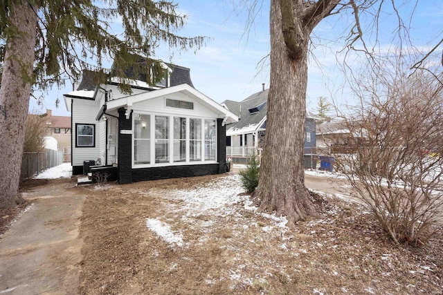 snow covered back of property featuring a sunroom