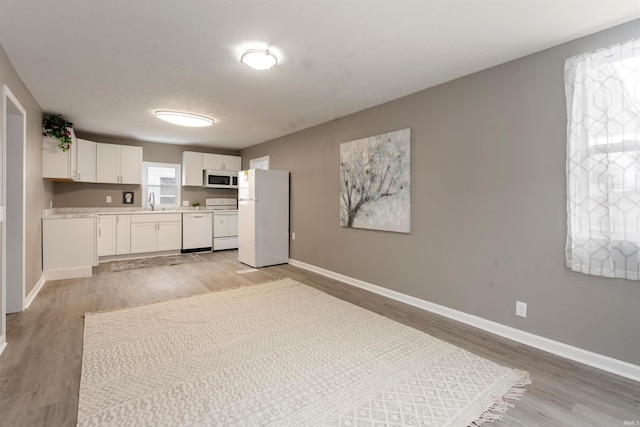 kitchen featuring white cabinets, a textured ceiling, white appliances, and light hardwood / wood-style flooring