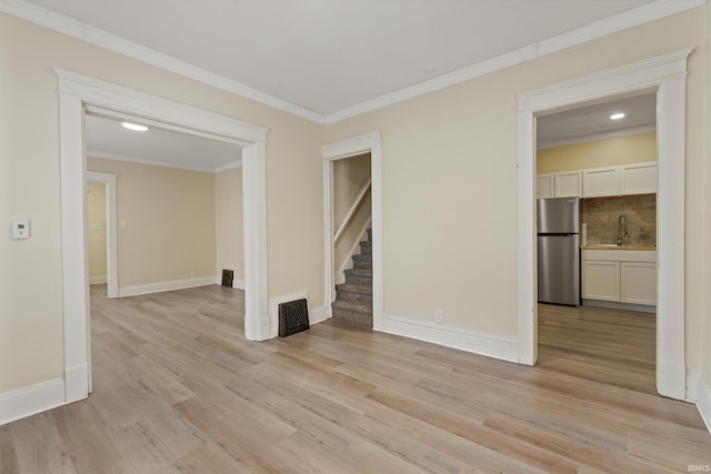 empty room with light hardwood / wood-style flooring, crown molding, and sink