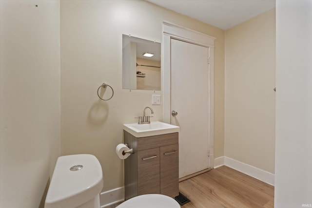 bathroom with wood-type flooring, vanity, and toilet