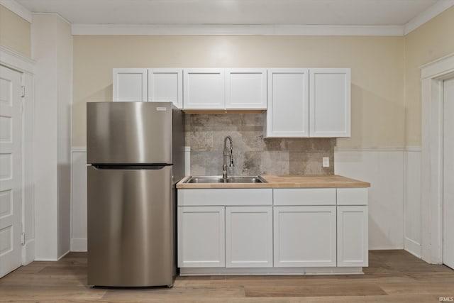 kitchen featuring stainless steel fridge, white cabinetry, and sink