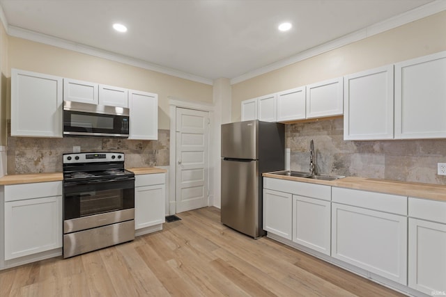 kitchen with wood counters, sink, white cabinetry, and stainless steel appliances