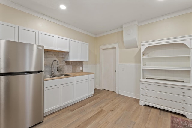 kitchen with sink, light hardwood / wood-style flooring, stainless steel fridge, crown molding, and white cabinets