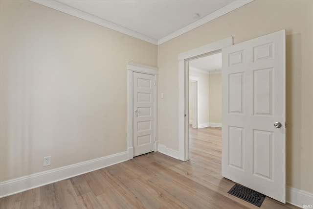 spare room featuring crown molding and light hardwood / wood-style floors