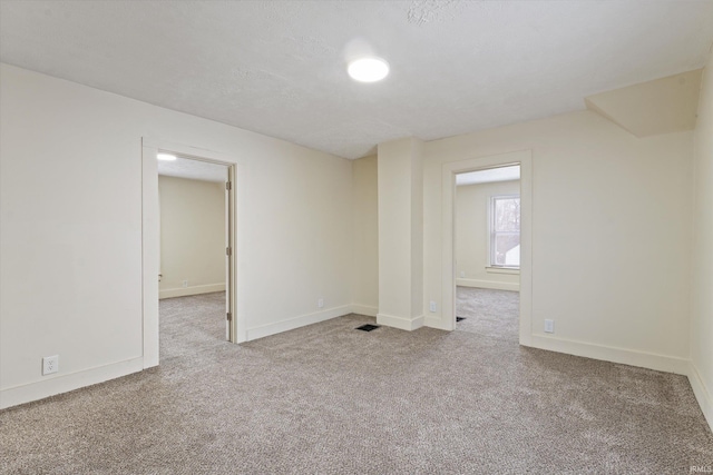 empty room with a textured ceiling and light carpet