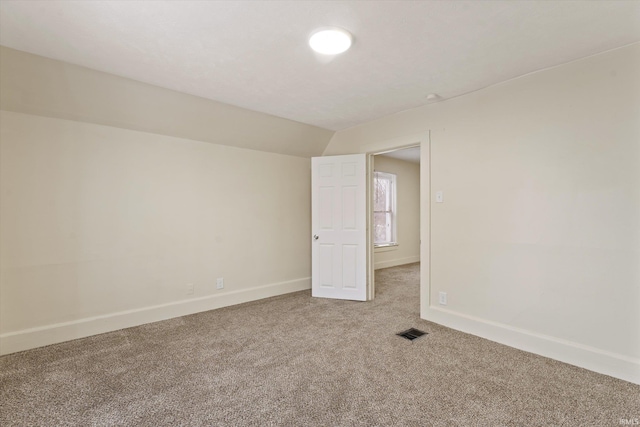 empty room with carpet floors and vaulted ceiling