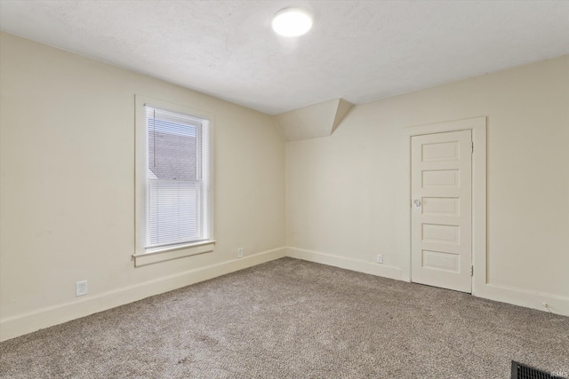 empty room with a textured ceiling, carpet, and lofted ceiling