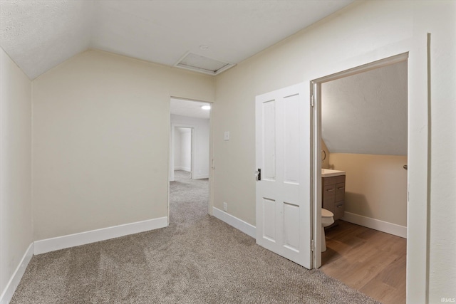 hallway with carpet flooring, a textured ceiling, and vaulted ceiling