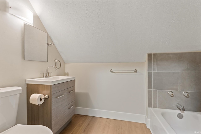 bathroom featuring vanity, lofted ceiling, a bathing tub, toilet, and wood-type flooring