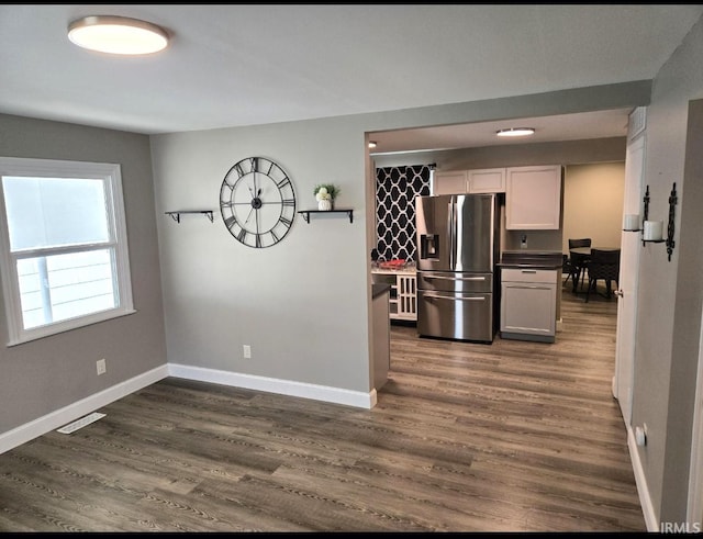 kitchen featuring stainless steel fridge, white cabinets, and dark wood-type flooring