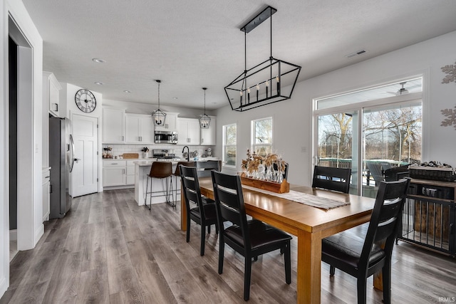 dining room with wood-type flooring, a textured ceiling, and sink