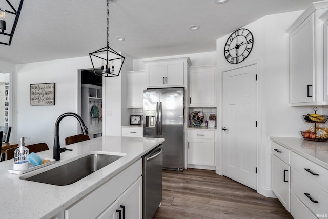 kitchen featuring light stone countertops, backsplash, stainless steel appliances, sink, and white cabinets