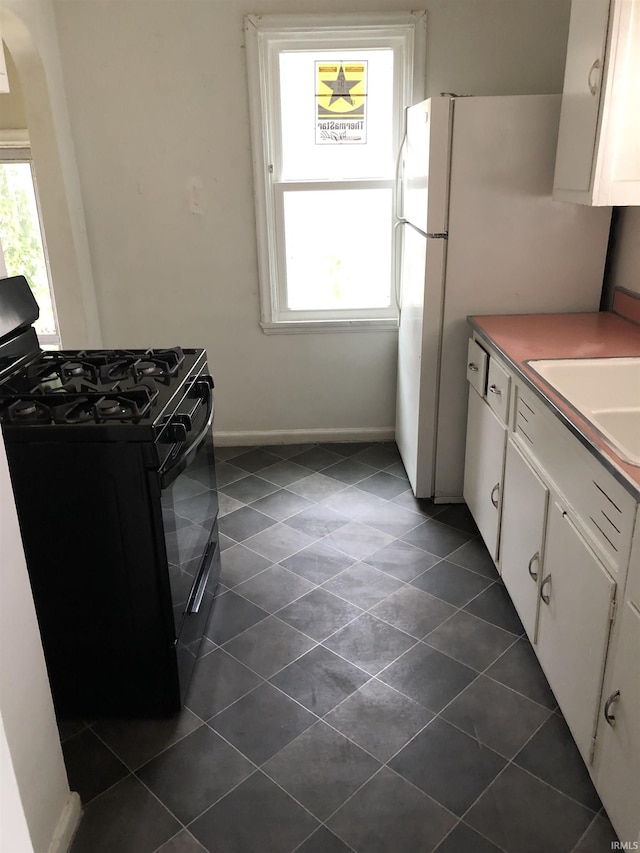 kitchen with dark tile patterned flooring, sink, white cabinetry, and black range with gas cooktop