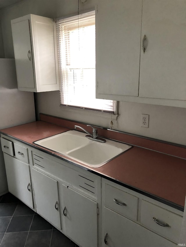 kitchen featuring sink, white cabinets, and dark tile patterned flooring