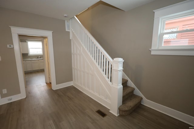 staircase with wood-type flooring and sink