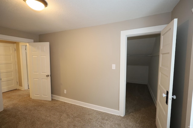 unfurnished bedroom with a walk in closet, carpet floors, and a closet