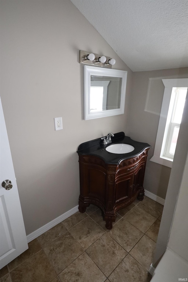 bathroom with vanity, plenty of natural light, lofted ceiling, and a textured ceiling