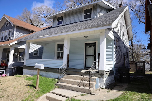 view of front of house featuring roof with shingles, a porch, and a chimney