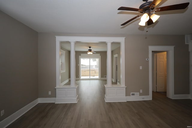 empty room with dark hardwood / wood-style floors, ceiling fan, and ornate columns