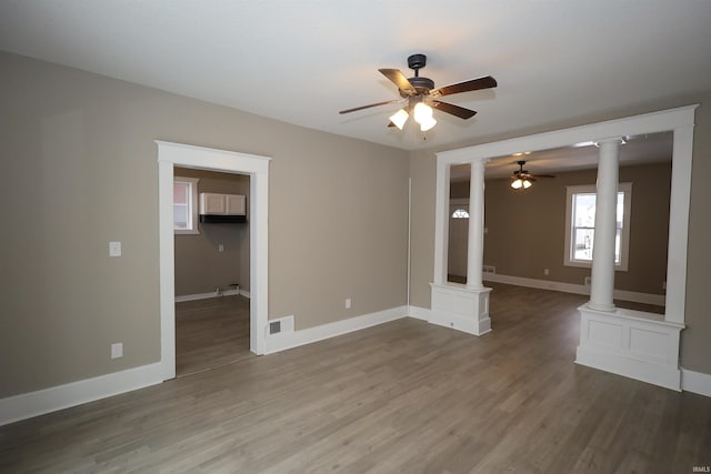 interior space with wood-type flooring, ceiling fan, and ornate columns