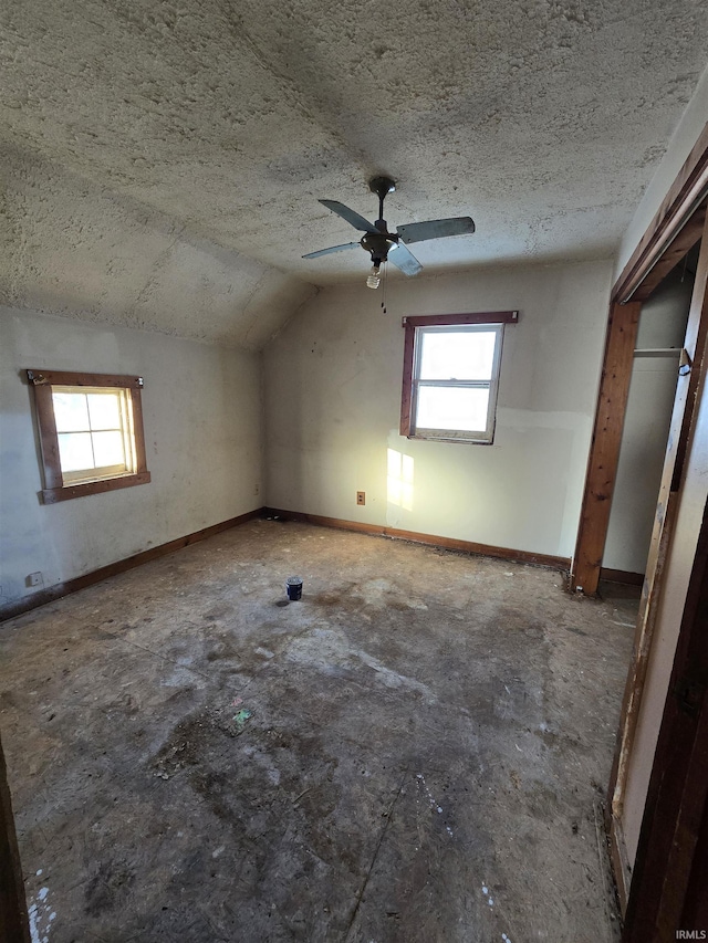 interior space with ceiling fan, a textured ceiling, and vaulted ceiling