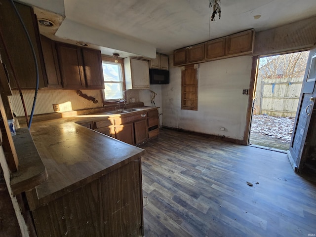 kitchen with decorative backsplash, kitchen peninsula, sink, and dark wood-type flooring