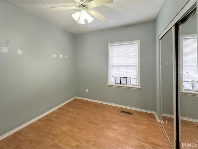 spare room with a textured ceiling, light wood-type flooring, and ceiling fan