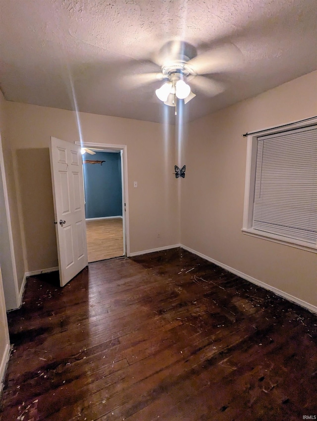 empty room featuring a textured ceiling, ceiling fan, and dark hardwood / wood-style floors