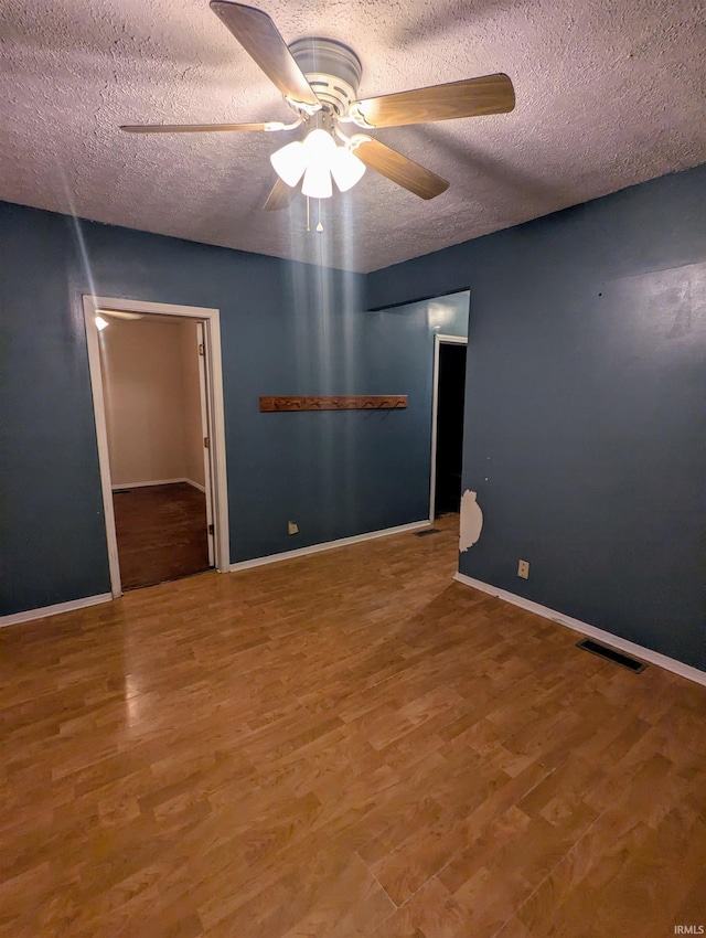 empty room with hardwood / wood-style floors, ceiling fan, and a textured ceiling