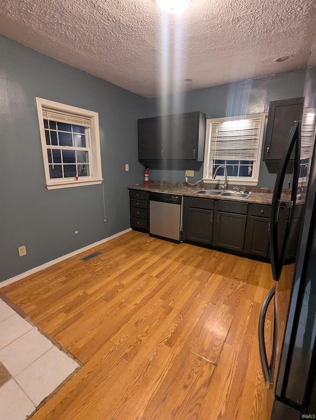 kitchen with black fridge, a textured ceiling, sink, light hardwood / wood-style flooring, and dishwasher