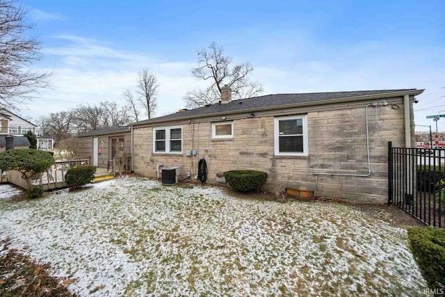 snow covered back of property featuring central AC unit