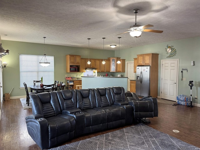 living room featuring ceiling fan, dark wood-type flooring, and a textured ceiling